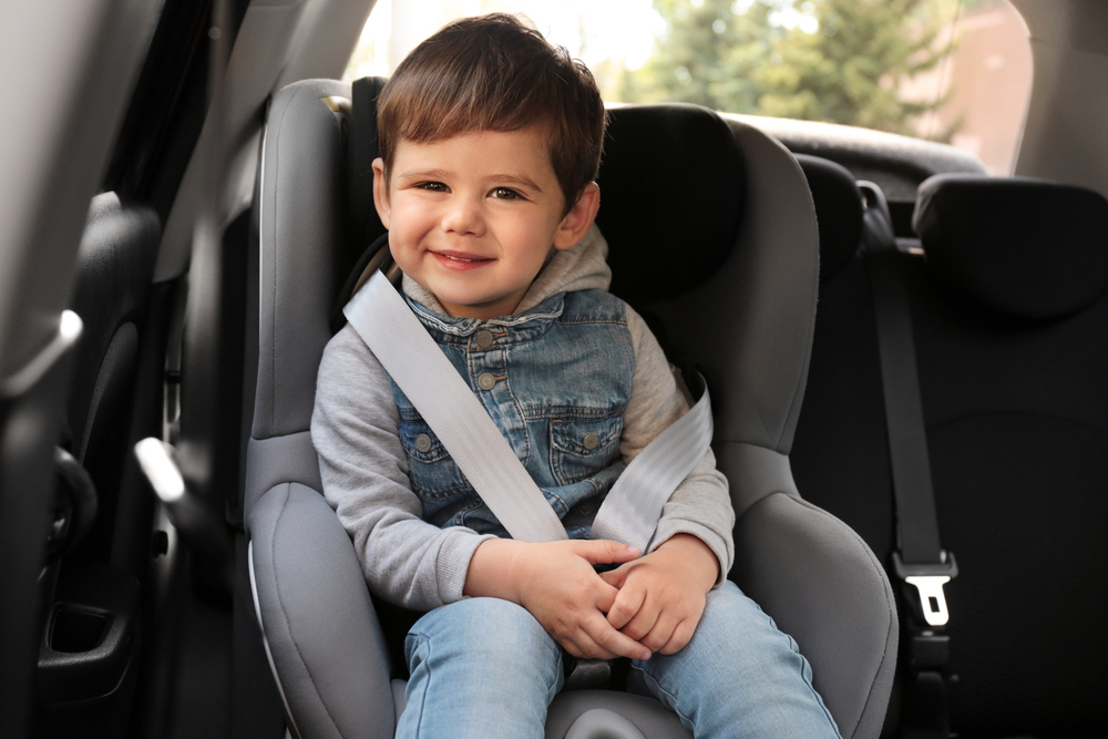 Cute toddler boy sitting in car seat