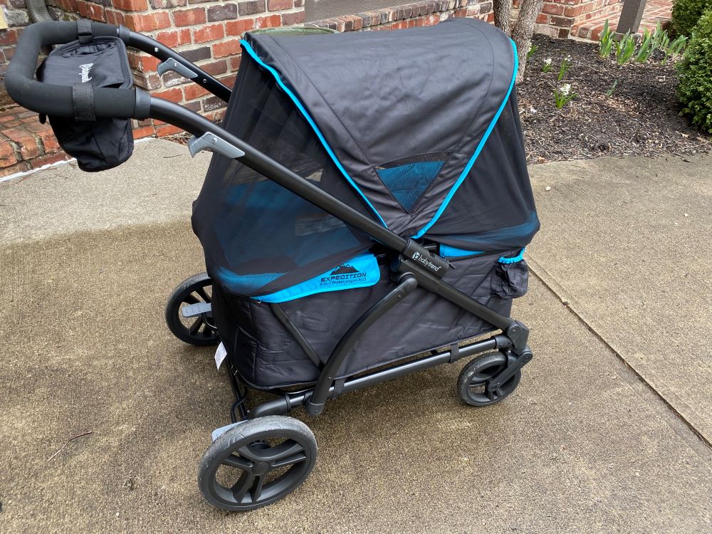 baby trend expedition wagon with the mosquito netting rolled down from the canopy on both ends