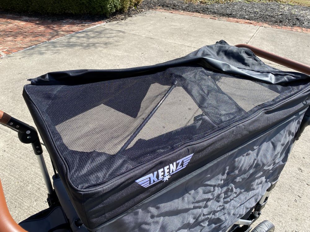 Keenz shown with canopy open revealing mesh fabric for ventilation of the top, and sun shade down blocking sun from the side