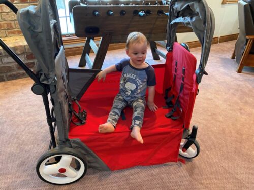 The Radio Flyer Discovery wagon in bench mode with the side zipped down and a toddler sitting facing out.