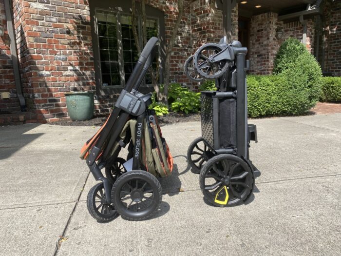 Evenflo and veer wagons folded and in standing position side by side. Evenflo on left, veer on right.