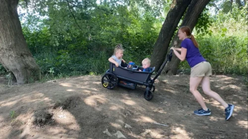 Mom pushing veer cruiser offroad with 2 kids