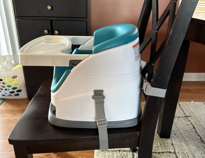 Side view of the ingenuity baby 2 in 1 portable high chair showing straps attached under the chair and to the chair seat back