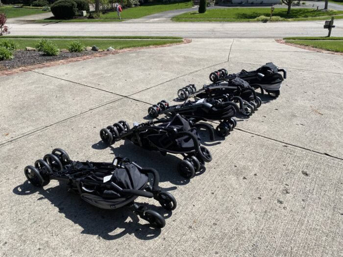 5 umbrella style strollers laying on the driveway folded