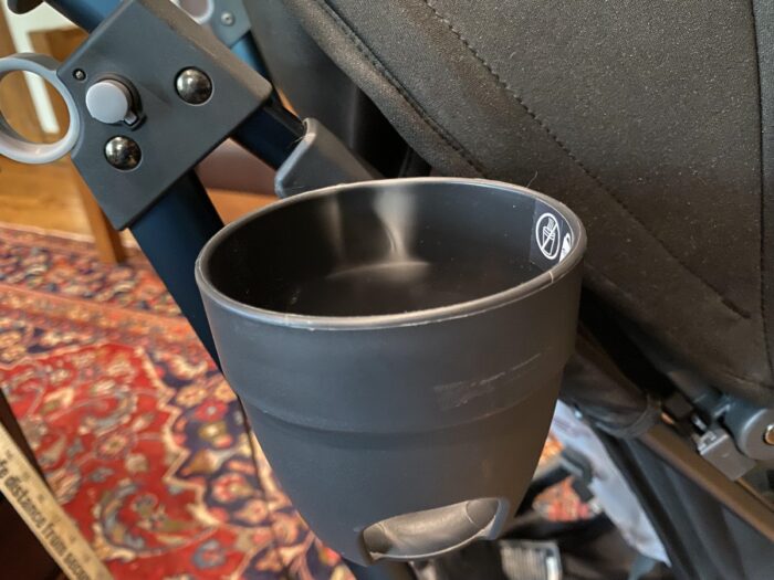 the uppababy cup holder showing white stress marks on the plastic near where it connects to the stroller frame, and scratches on the outside surface