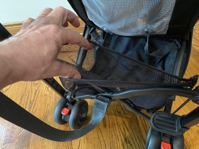 mesh pocket on g-lite stroller, showing fingers opening it